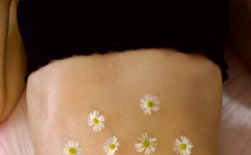Woman's belly adorned with calming chamomile flowers for relaxation therapy.