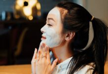 Маска с содой для омоложения: лучшие рецепты Asian woman relaxing with a face mask, practicing skincare in a cozy home environment.