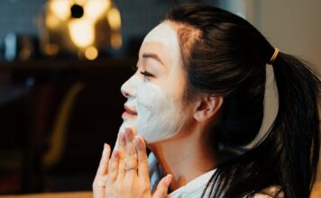Маска с содой для омоложения: лучшие рецепты Asian woman relaxing with a face mask, practicing skincare in a cozy home environment.
