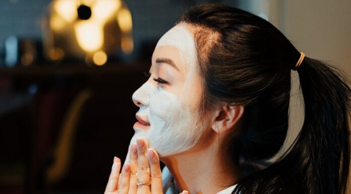 Asian woman relaxing with a face mask, practicing skincare in a cozy home environment.
